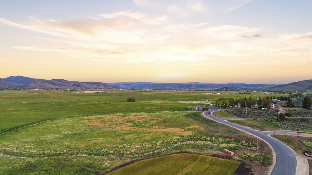 Evening light over open fields and a winding road in Kamas Valley